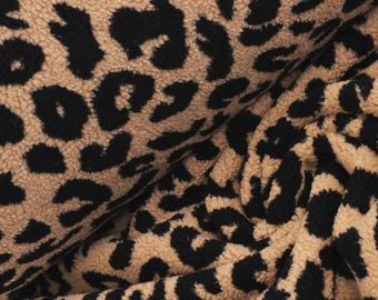 May include: A plush, textured fabric featuring a repeating leopard print pattern in shades of tan and black. The material has a soft, fuzzy surface with deep folds and ripples that create a sense of depth and dimension across the entire textile.