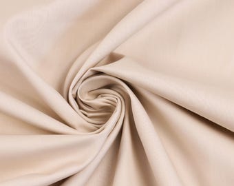 May include: A solid light beige fabric with a smooth, matte texture, arranged in a central spiral fold that creates soft, flowing drapes and deep shadows radiating outward from the center, highlighting the consistent color and fine weave.