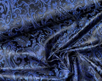 May include: A fabric featuring a black base with a vibrant blue woven paisley pattern. The material has a smooth, reflective finish with intricate, swirling teardrop motifs that create a dense, textured appearance across the folded surface.
