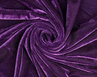 May include: A deep purple velvet fabric featuring a dense, soft pile with a distinct sheen. The material is arranged in a swirling, circular pattern that creates natural folds and shadows, highlighting the rich texture and vibrant violet color.