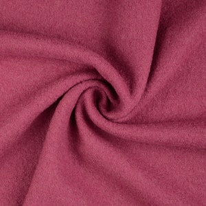 Könnte beinhalten: Nahaufnahme eines weichen, rosafarbenen Stoffes mit einer strukturierten Oberfläche. Der Stoff ist gefaltet und drapiert und erzeugt einen glatten, fließenden Look.