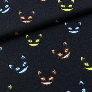 Tela de jersey de algodón con caras coloridas del Gato de Cheshire sobre fondo negro desde 0,5 m (18,00/metro)