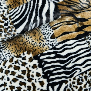Op de afbeelding: Een close-up van een stof met een patchwork-ontwerp met verschillende dierenprints, waaronder zebra, luipaard en cheetah. De stof is bruin, zwart en wit.