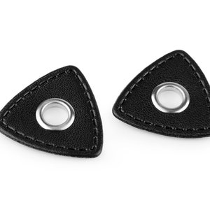 Op de afbeelding: Twee zwarte leren gitaarplectrums met een zilveren metalen gat in het midden.