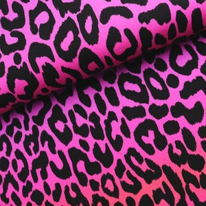 Può includere: Primo piano di un tessuto con una vivace stampa leopardata rosa e nera. Il tessuto è piegato, rivelando il motivo a macchie ripetute. La sfumatura di colore passa da un rosa intenso a una tonalità più chiara.