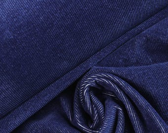 May include: A deep navy blue corduroy fabric featuring a distinct vertical ribbed texture. The material is folded to show the soft, matte surface of the textile, with the underside of the fabric revealing lighter, white-toned vertical lines.