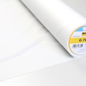 Op de afbeelding: Een rol witte stof met een label met de tekst "G 785". De stof is 90 cm x 25 m en gemaakt van 100% PES. De stof is opgerold en klaar voor naai- of knutselprojecten.