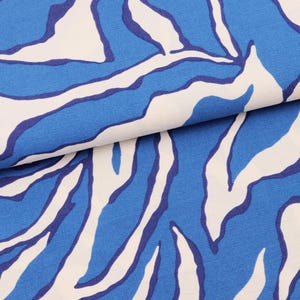 Pode incluir: Tecido azul e branco com um padrão abstrato em espiral. O tecido tem uma superfície texturizada.