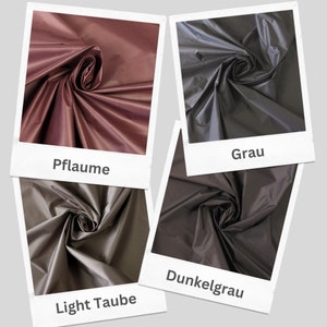 May include: Four fabric swatches in different shades of gray, plum, and taupe. The swatches are arranged in a grid pattern and each swatch has a label underneath it. The labels read "Pflaume", "Grau", "Dunkelgrau", and "Light Taube".