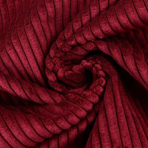 Peut inclure: Gros plan sur un tissu en velours côtelé rouge foncé avec une surface texturée et côtelée. Le tissu est plié et tordu, créant un motif tourbillonnant.