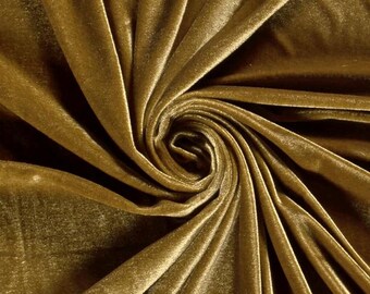 May include: A solid gold-colored velvet fabric featuring a dense, soft pile texture. The material is arranged in a central spiral swirl pattern, creating deep shadows and bright highlights across the surface of the lustrous, reflective textile.