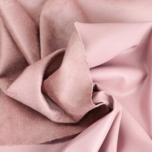 Puede incluir: Primer plano de una tela suave y rosa con una textura suave y aterciopelada. La tela está doblada y drapeada, mostrando su tacto lujoso.