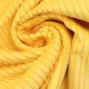 Könnte beinhalten: Nahaufnahme eines leuchtend gelben Cordstoffs. Der Stoff ist gefaltet und gewirbelt, wodurch die Textur und das vertikale Rippenmuster zur Geltung kommen. Die Farbe ist ein helles, sonniges Gelb.