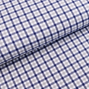 Könnte beinhalten: Nahaufnahme eines weißen Stoffes mit einem karierten Muster in Blau und Grau. Der Stoff ist in der Mitte gefaltet, sodass das Muster auf beiden Seiten sichtbar ist.