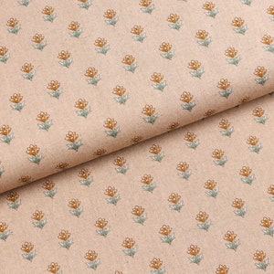 Op de afbeelding: Een beige stof met een herhalend patroon van kleine oranje bloemen. De stof is dubbelgevouwen, waardoor het patroon aan beide kanten zichtbaar is.