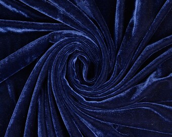 May include: A deep navy blue velvet fabric featuring a dense, soft pile with a light-reflecting sheen. The material is arranged in a central spiral swirl pattern, creating natural folds and shadows that highlight the rich, saturated color.