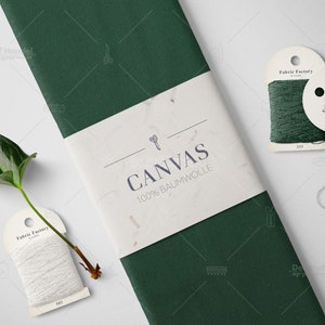 Puede incluir: Un rollo de tela verde oscuro con una etiqueta blanca que dice "CANVAS 100% BAUMWOLLE". Se muestran dos carretes de hilo, uno blanco y otro verde, con etiquetas que dicen "Fabric Factory".