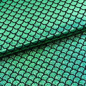 Può includere: Tessuto verde con un motivo a squame di sirena. Le squame sono contornate di nero e hanno una finitura glitterata.