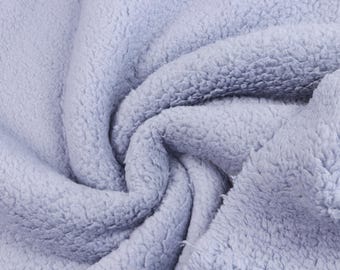 May include: A light lavender-colored fabric with a thick, plush, and fuzzy sherpa-like texture. The material is gathered into soft, deep folds, highlighting the dense, curly pile surface that creates a consistent, monochromatic appearance throughout.