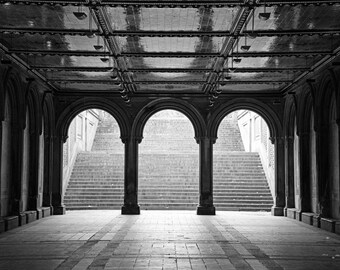May include: A black and white photo of a stone archway with three arches leading to a set of stairs. The arches are lined with columns and the stairs are made of stone.