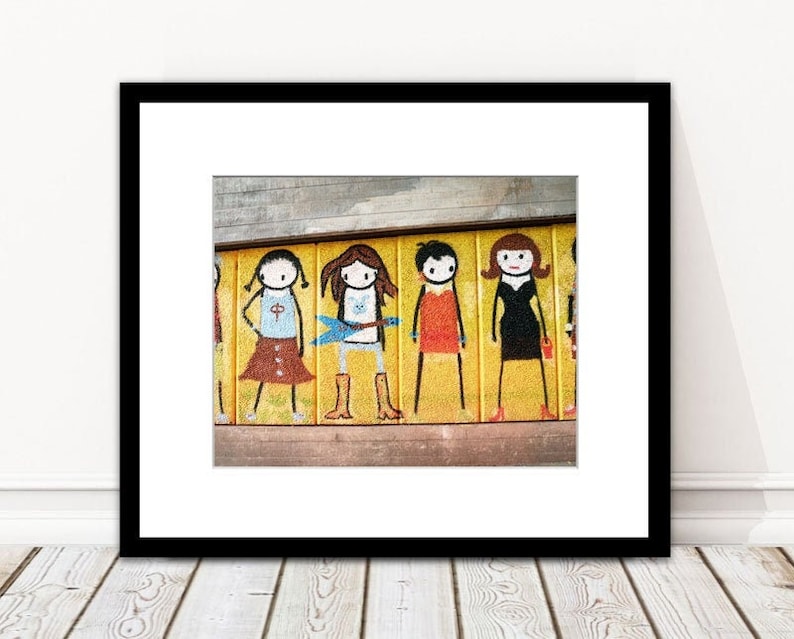 K&ouml;nnte beinhalten: Ein farbenfrohes Wandbild an einer gelben Wand zeigt f&uuml;nf Strichm&auml;nnchen, jedes mit einer anderen Frisur und einem anderen Outfit. Die Figuren stehen in einer Reihe und blicken nach vorne. Das Wandbild ist in einem einfachen, cartoonartigen Stil gemalt.