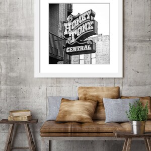 May include: Black and white photograph of a neon sign that reads "Honky Tonk Central". The sign is mounted on a brick building.