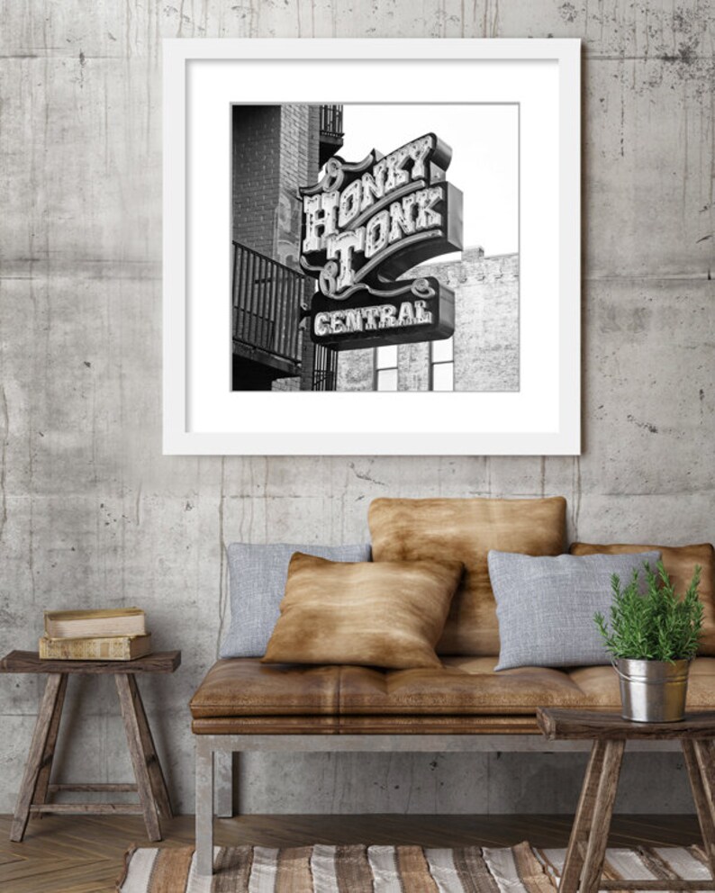 May include: Black and white photograph of a neon sign that reads "Honky Tonk Central". The sign is mounted on a brick building.
