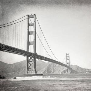 May include: A black and white photograph of the Golden Gate Bridge in San Francisco, California. The bridge is a suspension bridge with two towers and a long span.