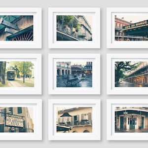 Pu&ograve; includere: Nove cornici per foto bianche con passpartout neri, ciascuna contenente una fotografia diversa di New Orleans, Louisiana. Le foto includono scene di strada, edifici e cartelli. Le cornici sono disposte in tre file di tre.