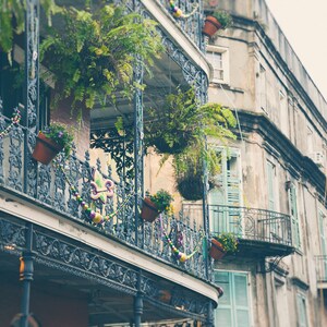 Pu&ograve; includere: Un edificio d'epoca con un balcone in ferro battuto decorato con perline viola, verdi e dorate. Il balcone ha diverse piante e fiori in vaso. L'edificio &egrave; dipinto in tonalit&agrave; di grigio e bianco.