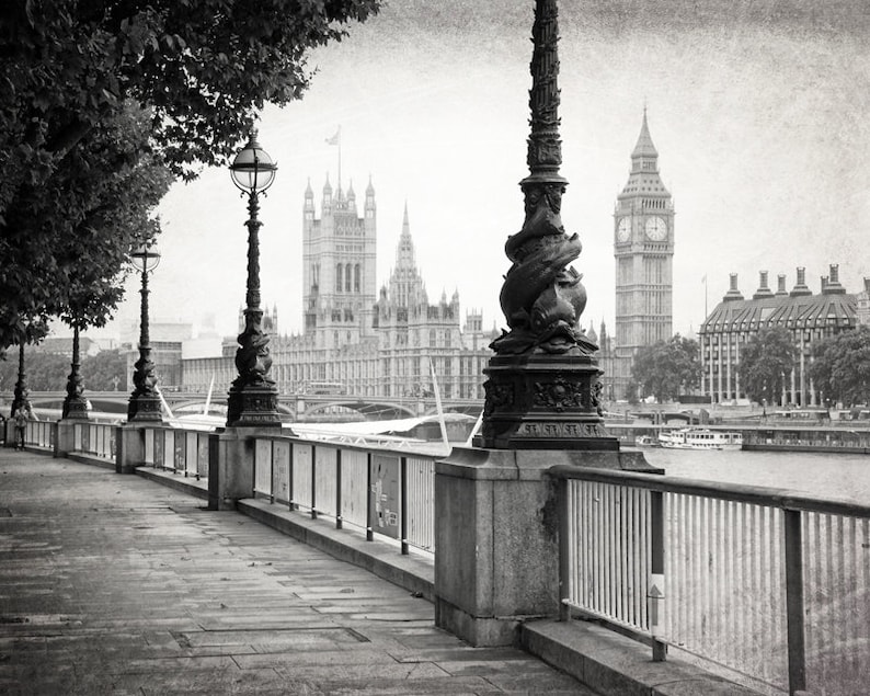 Op de afbeelding: Een zwart-witfoto van een trottoir langs de Theems in Londen, Engeland. De Houses of Parliament en Big Ben zijn op de achtergrond te zien.