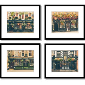 May include: Four framed photographs of London pubs with floral decorations above the entrances. The pubs are all brick buildings with black frames and windows. The photos are in black and white with a vintage filter.
