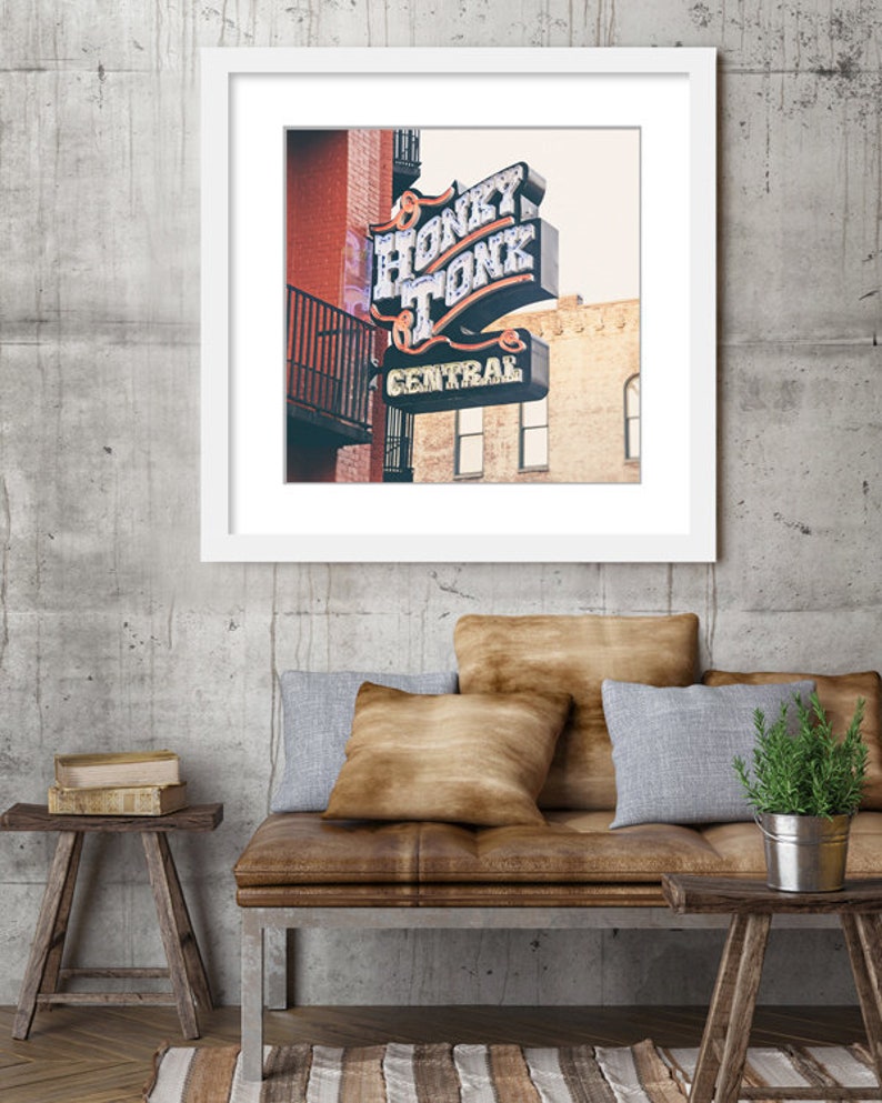 May include: A vintage neon sign with the words "Honky Tonk Central" in white letters on a blue background. The sign is mounted on a brick building with a balcony.