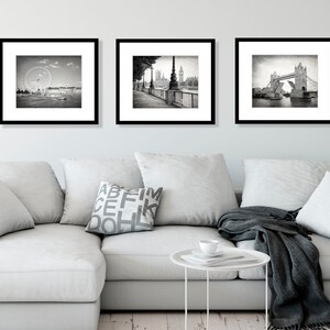 Op de afbeelding: Drie zwart-witte ingelijste foto's van Londense bezienswaardigheden. De eerste foto toont het London Eye reuzenrad. De tweede foto toont een straatbeeld met uitzicht op Big Ben. De derde foto toont de Tower Bridge.