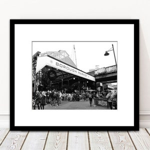 May include: Monochrome framed print featuring Borough Market, London. The image shows the market's entrance, with "BOROUGH MARKET" written above. Several people are visible, suggesting a bustling market scene.