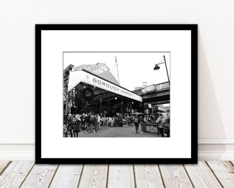 May include: Monochrome framed print featuring Borough Market, London. The image shows the market's entrance, with "BOROUGH MARKET" written above. Several people are visible, suggesting a bustling market scene.