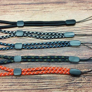 May include: Four different types of eyeglass retainers with black plastic ends. The retainers are made of braided cord in black, white and blue, black, blue and white, black, green and white, and orange, white and black.