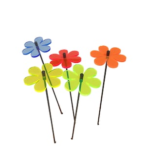 May include: Five colourful acrylic flowers on black metal stems. The flowers are in shades of blue, red, yellow, and green.