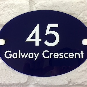May include: Oval-shaped house number sign with white text on a dark blue background. The sign reads "45 Galway Crescent".