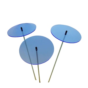 May include: Three blue glass discs on metal stands. The discs are round and have a slight curve to them. The stands are thin and silver.