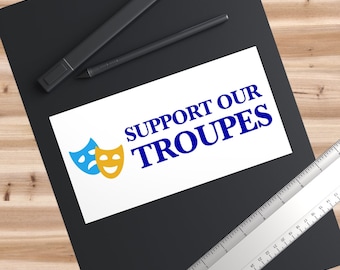 May include: White sticker with blue text that says "SUPPORT OUR TROUPES" and a blue and yellow theater mask graphic.