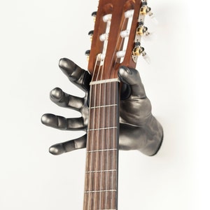 Classic Grip hand guitar hanger from GuitarGrip. Silver Antique Finish. Right Hand holding Classical Guitar.