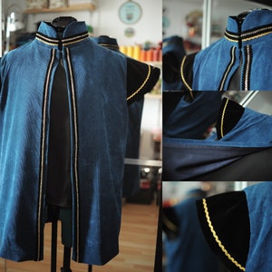May include: A blue corduroy vest with black velvet sleeves and gold trim. The vest has a high collar and a front opening. The sleeves are short and flared. The gold trim is along the collar, front opening, and sleeve edges.