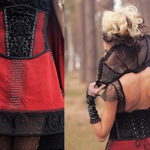 May include: A red and black corset dress with intricate detailing. The bodice features a black velvet panel with an ornate pattern, accented with small embellishments. The skirt is a vibrant red, with delicate lace and beadwork. The dress has a gothic or fantasy theme.