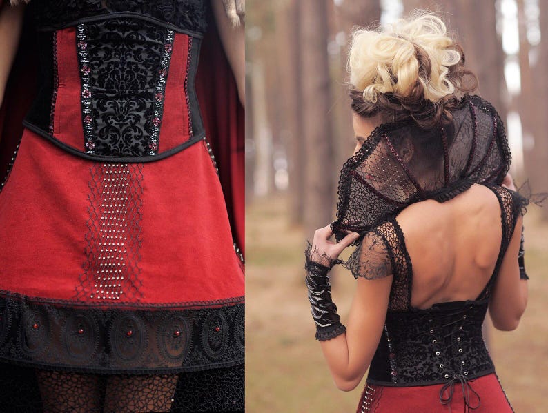 May include: A red and black corset dress with intricate detailing. The bodice features a black velvet panel with an ornate pattern, accented with small embellishments. The skirt is a vibrant red, with delicate lace and beadwork. The dress has a gothic or fantasy theme.