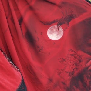 May include: Red fabric with a black illustration of a raven in flight, a full moon, and a castle. The fabric has black lace trim and white polka dots. The overall theme is gothic.