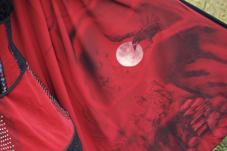 May include: Red fabric with a black illustration of a raven in flight, a full moon, and a castle. The fabric has black lace trim and white polka dots. The overall theme is gothic.