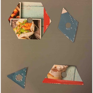 May include: Four differently shaped pieces of paper with a hole punched in the centre. Each piece has a different image printed on it. The images include a sandwich, a dessert, and a blue background with white dots.
