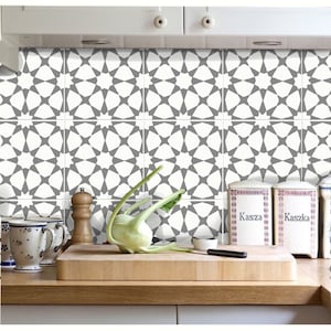 Puede incluir: Cocina con salpicadero de azulejos estampados en blanco y gris. Los azulejos presentan un dise&ntilde;o de estrella geom&eacute;trica repetitiva. Una tabla de cortar de madera, verduras y botes est&aacute;n en la encimera.