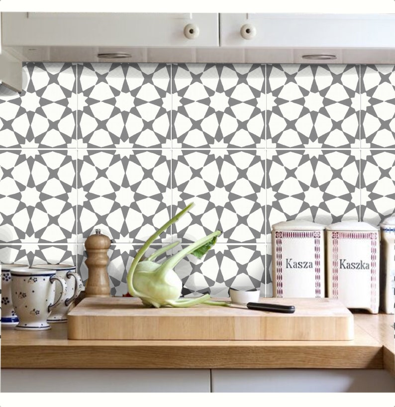 Puede incluir: Cocina con salpicadero de azulejos estampados en blanco y gris. Los azulejos presentan un dise&ntilde;o de estrella geom&eacute;trica repetitiva. Una tabla de cortar de madera, verduras y botes est&aacute;n en la encimera.